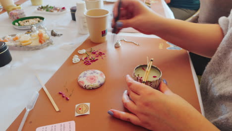 Woman-placing-the-decoration-with-tweezers-on-the-candle-during-candle-creation-workshop