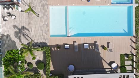 Aerial-top-down-shot-of-terrace-with-empty-swimming-pool-during-sunny-day-in-Hotel-Area