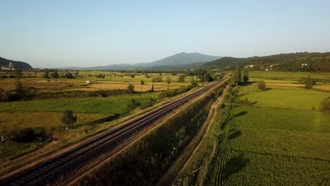 Train-move-on-railway-wonderful-moment-cinematic-perspective-scenic-landscape-of-Hyrcanian-forest-mountain-view-panoramic-green-meadow-rice-paddy-farm-land-field-summer-agriculture-iran-gilan-travel