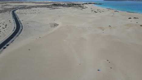 Aerial-view-above-the-road-through-the-sand-dunes-at-Corralejo-Beach-in-Fuerteventura,-Canary-Island,-Spain