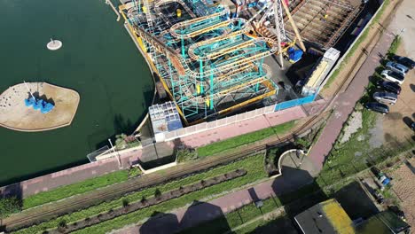 Aerial-drone-shot-of-Hastings-UK,-Pull-away-pan-up-shot-of-amusement-park,-old-town-and-Land-Based-Fishing-Fleet