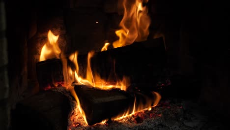 Log-slow-burning-cozy-warm-fireplace,-hard-wood-pile-big-flames