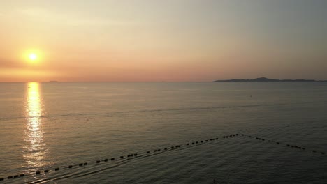 Wunderschöner-Goldener-Sonnenuntergang,-Der-Sich-Auf-Der-Oberfläche-Eines-Ruhigen-Meeres-Mit-Inseln-In-Der-Ferne-Spiegelt