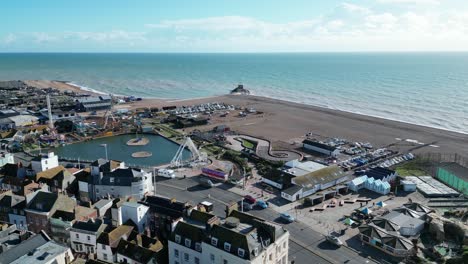Aerial-drone-shot-of-Hastings-UK,-flying-over-beach-town,-amusement-park-and-Land-Based-Fishing-Fleet