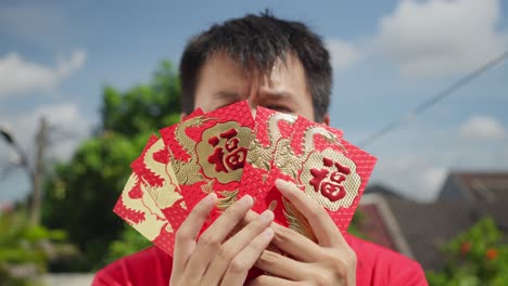 Asian-male-showing-to-camera-several-hongbao-in-hand