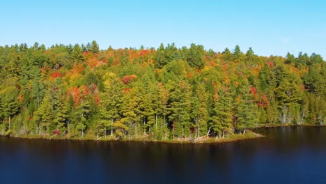 Aerial-Flying-Towards-Oncoming-Fall-Foliage-Beside-Lake,-Near-Montreal,-Canada