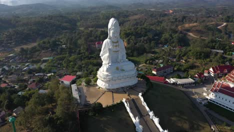 Aerial-drone-of-Wat-Huay-Pla-Kang-giant-white-big-statue-and-pagoda-temples-with-mountains-and-landspace-in-Chiang-Rai,-Thailand