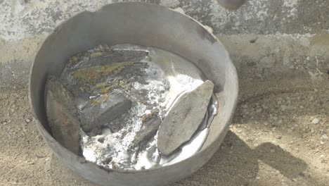 Molten-lead-in-a-metal-container-with-a-propane-torch-heating,-close-up