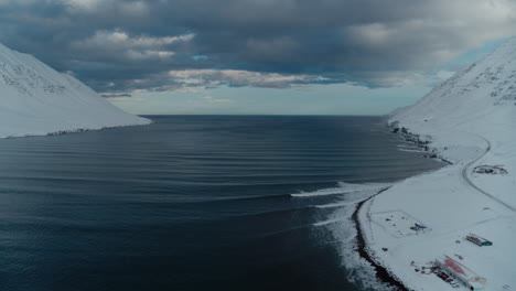 Montañas-Nevadas-Que-Rodean-Un-Fiordo-Congelado-En-Islandia-Durante-El-Invierno-Tomadas-Desde-Un-Dron
