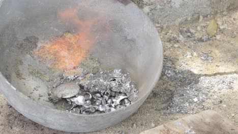 Molten-lead-in-a-crucible-with-visible-flames-and-fumes,-in-an-industrial-setting,-top-down-view