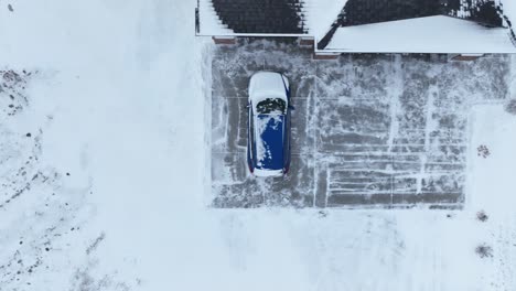 Overhead-drone-shot-of-a-car-covered-in-snow-in-a-frozen-driveway