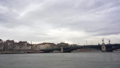 Flussszene:-Ankernde-Schiffe-Am-Ufer-Der-Rhone-In-Lyon,-Mit-Der-Alten-Eisenbrücke-Und-Klassischer-Architektur