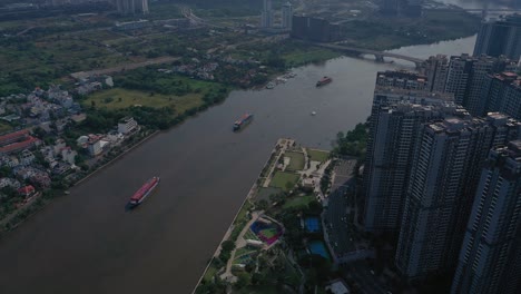 Landmark-and-surrounding-high-rise-buildings,-Saigon-river-with-container-boats