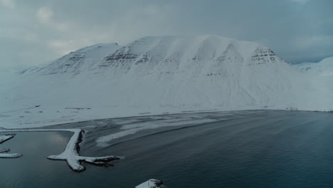 Snowy-mountains-above-a-frozen-Fjord-in-Iceland-during-winter-shot-from-a-drone