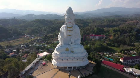 Aerial-drone-of-Wat-Huay-Pla-Kang-huge-white-big-statue-and-pagoda-with-mountains-and-landspace-in-Chiang-Rai,-Thailand
