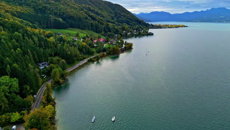 Aerial-dolly-forward-shot-over-scenic-route-through-Norway-with-green-forest-and-small-town-along-the-coast-of-the-fjord