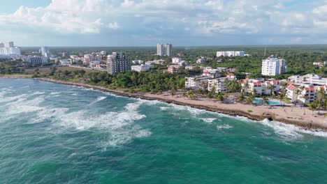 Aerial-establishing-drone-shot-showing-huge-waves-of-Caribbean-sea-reaching-coast-of-Juan-Dolio-with-hotels-and-villas