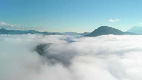 Vista-De-Cabina-Volando-A-Través-De-Las-Nubes,-Mar-De-Niebla-Con-Montañas-Alcanzando-Su-Punto-Máximo,-Valle-De-Montaña-Temprano-En-La-Mañana,-Espesa-Capa-De-Nubes-En-El-Valle-De-Montaña