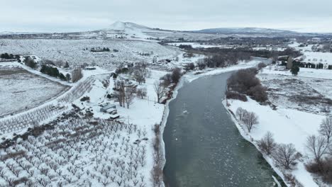Drone-shot-of-Benton-City's-rural-orchards-covered-in-snow-with-the-Yakima-River-running-through-the-frame
