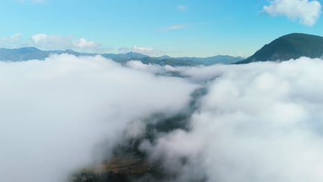Above-the-Cloud-Timelapse,-Clouds-opening-up-over-the-Mountain-Valley,-Cloud-Vanish,-Thick-Layer-of-Clouds-opening-up,-Blue-Sky-Mountain-Background,-Aerial-Drone