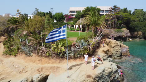 The-Greek-flag-stands-on-a-promontory-above-the-beaches-of-Agia-Pelagia-in-Crete