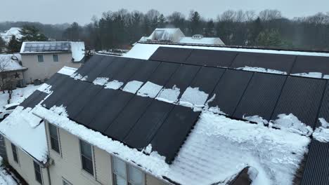 Solar-panels-on-snowy-roof-of-house-in-American-neighborhood-at-winter-season
