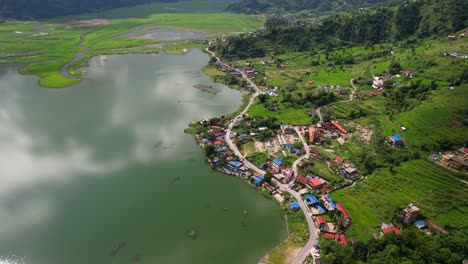 Stunning-aerial-view-of-a-village-on-Phewa-Lakeside,-drone-flying-down-in-Pokhara,-Nepal