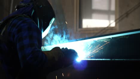 Welder's-craft-unfolds:-Sparks-dance-as-skilled-hands-shape-metal-in-a-bustling-industrial-scene,-captured-vividly-in-this-dynamic-stock-footage
