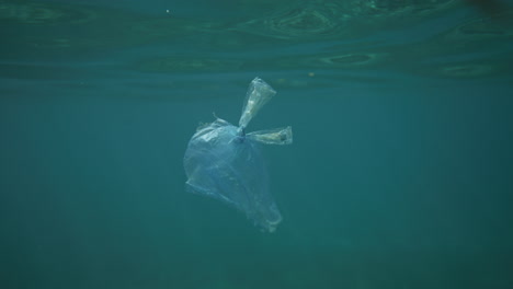 Plastic-bag-floating-in-crystal-clear-water-with-light-reflections-shot-from-underwater