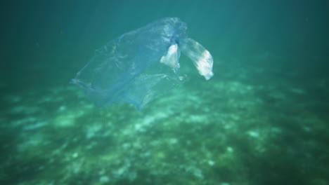 Plastic-bag-floating-in-crystal-clear-water-with-light-reflections-shot-from-underwater