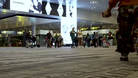 Travellers-Walking-Across-Hall-In-Terminal-Departures-Building-At-Changi-Airport