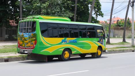 Cool,-funky-modified-bright-green-and-yellow-district-bus-transportation-with-person-waving-through-window,-parked-on-street-in-capital-city-of-East-Timor,-Southeast-Asia