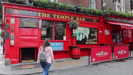 Woman-walks-towards-The-Temple-Bar,-famous-pub-in-Dublin-city-center