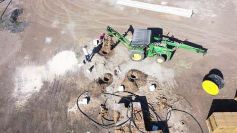 Aerial-drone-view-Tractor-digging-pit-for-wire-supply-several-solar-systems-are-visible
