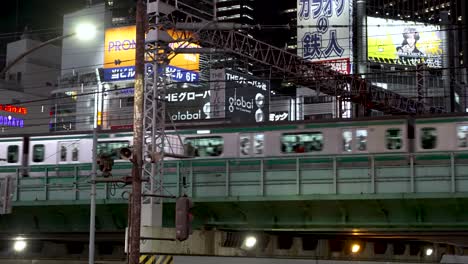 Vibrant-metropolis-of-Tokyo,-Japan,-a-Yamanote-line-train-swiftly-traverses-elevated-tracks-in-the-bustling-district-of-Shinjuku
