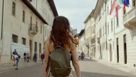 Attractive-young-woman-with-long-hair-walks-down-Italian-city-street,-solo-female-traveler