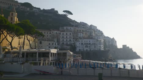 Tourists-on-Beachside-Below-Mountains-|-Amalfi-Coast-Italy-Travel-Tourism-Sunrise-Cliffside-Coastline,-Europe,-Walking,-4K