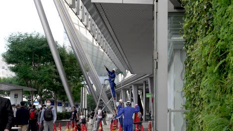 Wartungsarbeiter-Des-Tokioter-Bahnhofs-Putzen-Fenster-An-Der-Eingangsseite-Von-Yaesu,-Während-Pendler-Vorbeigehen