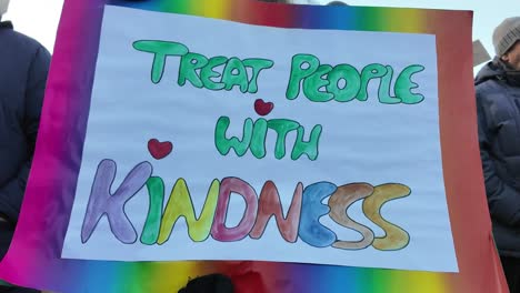 Woman-protesting-peacefully-with-a-sign-that-says-"treat-people-with-kindness