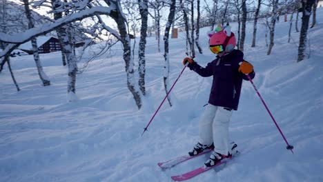 Girl-with-pink-helmet-skiing-towards-camera-and-passing-in-Myrkdalen-ski-resort-Norway,-slow-motion