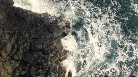 Pacific-ocean-waves-washing-rocky-coastline-of-Hawaii,-aerial-top-down-view