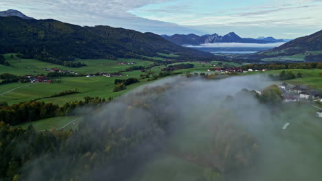 Wunderschöne-Luftaufnahme-über-Einer-Wolke-Des-Grünen-Feldes,-Umgeben-Von-Bergen,-Natur,-Bäumen-Und-Einem-Fernen-See