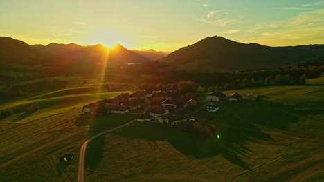 Wunderschöne-Aufnahmen-Mit-Sonnenstrahlen-In-Einer-Grünen-Wiese-Mit-Bergen-Und-Einigen-Häusern