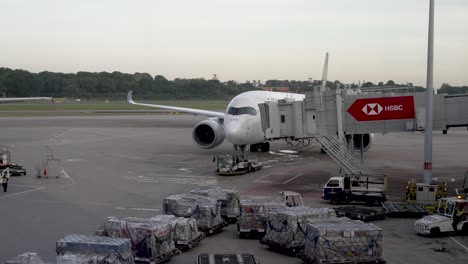 white-airplane-preparing-on-the-runway-to-fly,-surrounded-by-packages,-tarpaulins-and-cranes