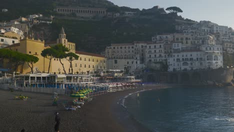 Travelers-Relaxing-On-Beach-at-Sunrise-|-Amalfi-Coast-Italy-Travel-Tourism-Sunrise-Cliffside-Coastline,-Europe,-Walking,-Shaky,-4K