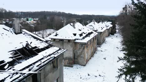 Aerial-view-of-row-of-abandoned,-dilapidated-buildings-in-a-snowy-landscape,-creating-an-eerie-and-desolate-atmosphere