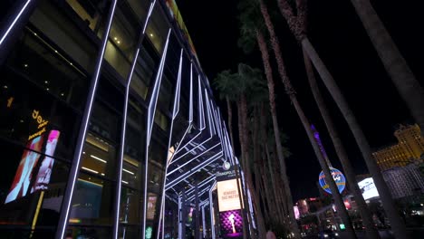 Rotating-view-looking-up-at-palm-trees-and-neon-lights-on-street,-Las-Vegas-nightlife