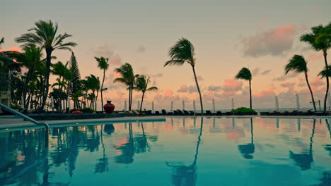 Beach-resort-with-outdoor-swimming-pool-and-high-palm-trees-at-sunset