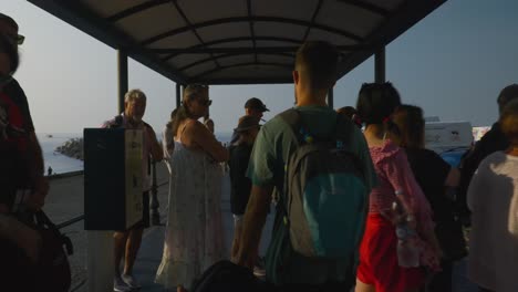 Man-In-Backpack-Walking-Through-Crowded-Tourist-Waiting-Area-|-Amalfi-Coast-Italy-Travel-Tourism-Sunrise-Cliffside-Coastline,-Europe,-Walking,-Shaky,-4K