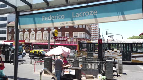 Street-Vendor-Sells-Pancakes-at-Federico-Lacroze-Railway-Station-in-Chacarita,-People-of-Argentina-walking-under-sunlight-in-Summer